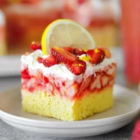 Strawberry Lemonade Poke Cake: A Refreshing Summer Treat Strawberry Lemonade Poke Cake Slice on a Plate